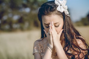 鼻と口を押さえて目を閉じるアジア人女性