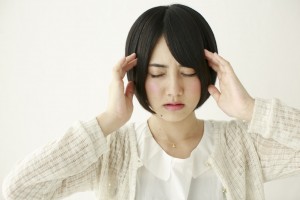 こめかみを押さえる頭痛の女性